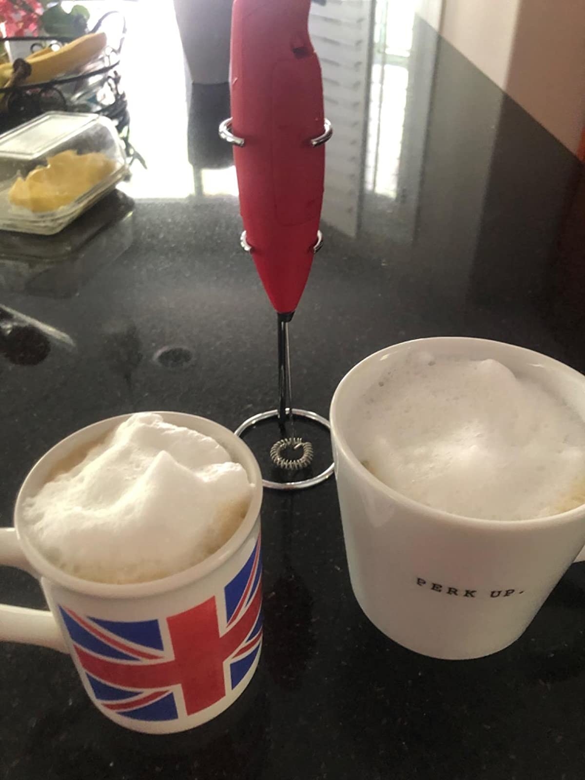 Reviewer image of two mugs filled with frothy drinks and milk frother behind them