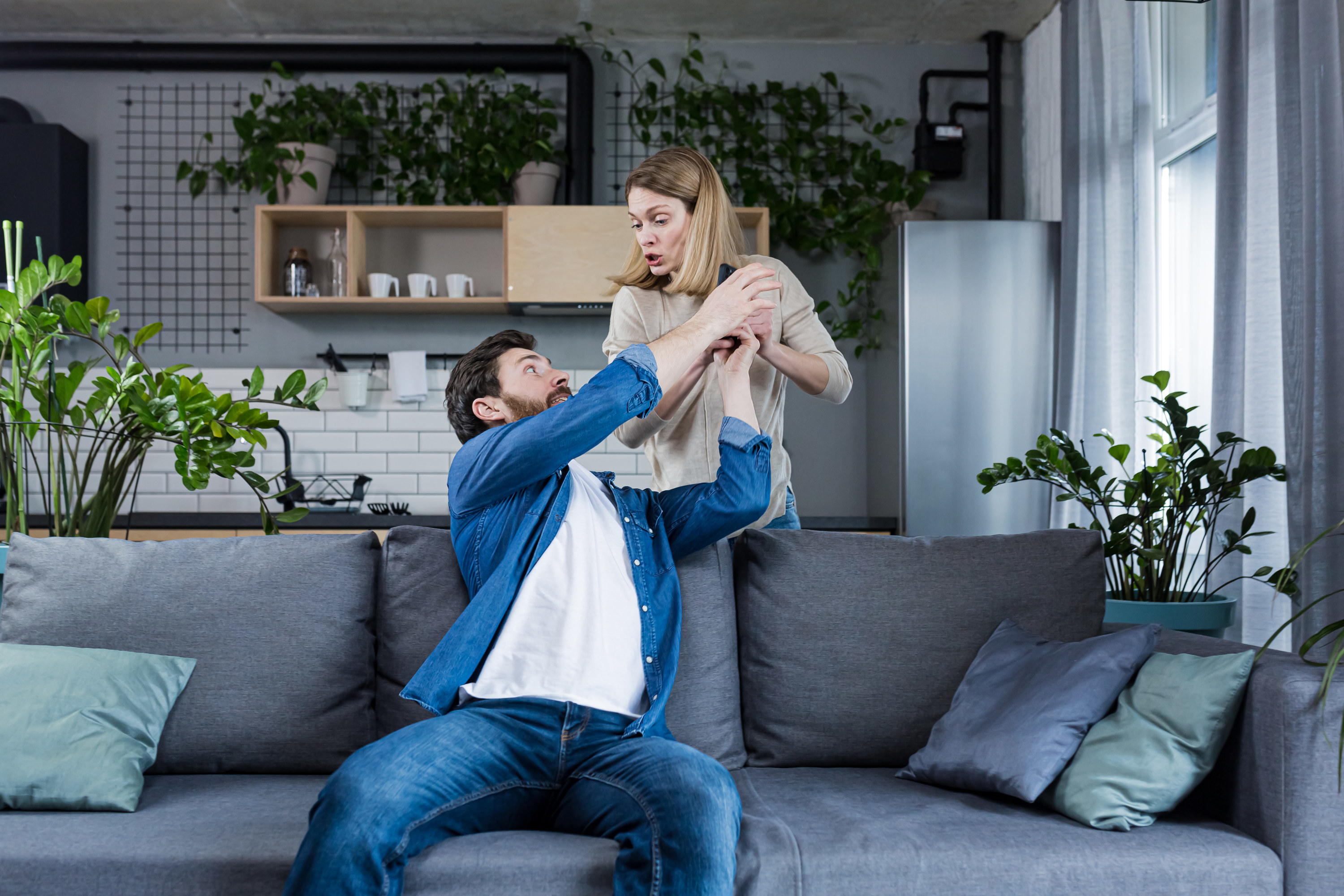 A man trying to grab his partner&#x27;s phone out of her hands