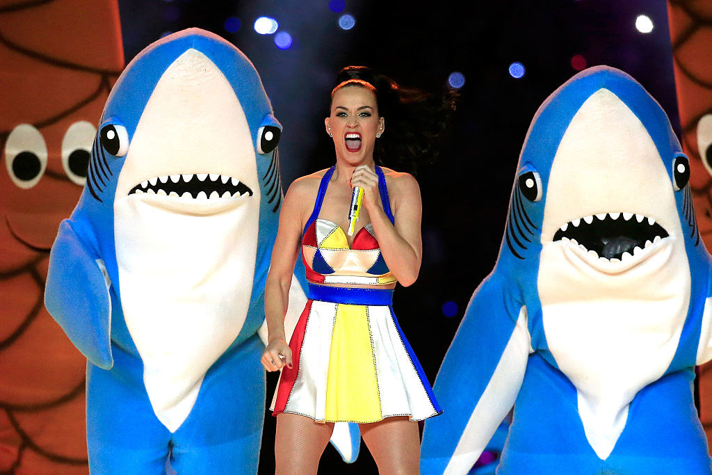 Katy performing between two people in shark costumes