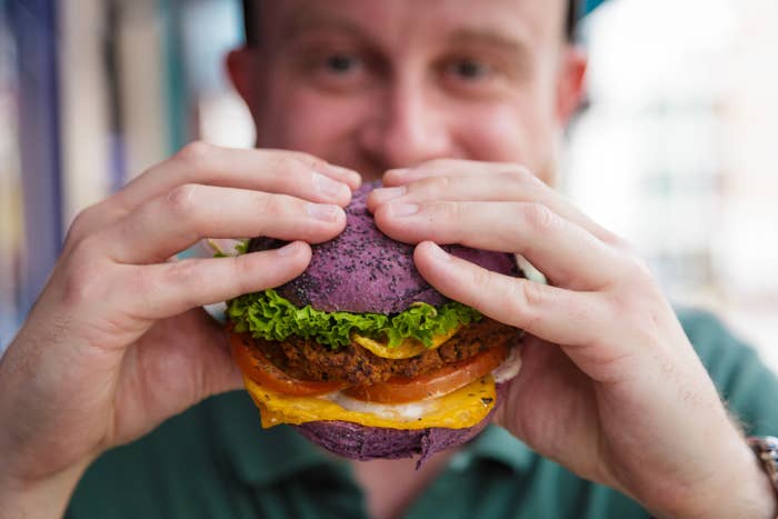 adult man in his 30s holding a freshly prepared vegan burger