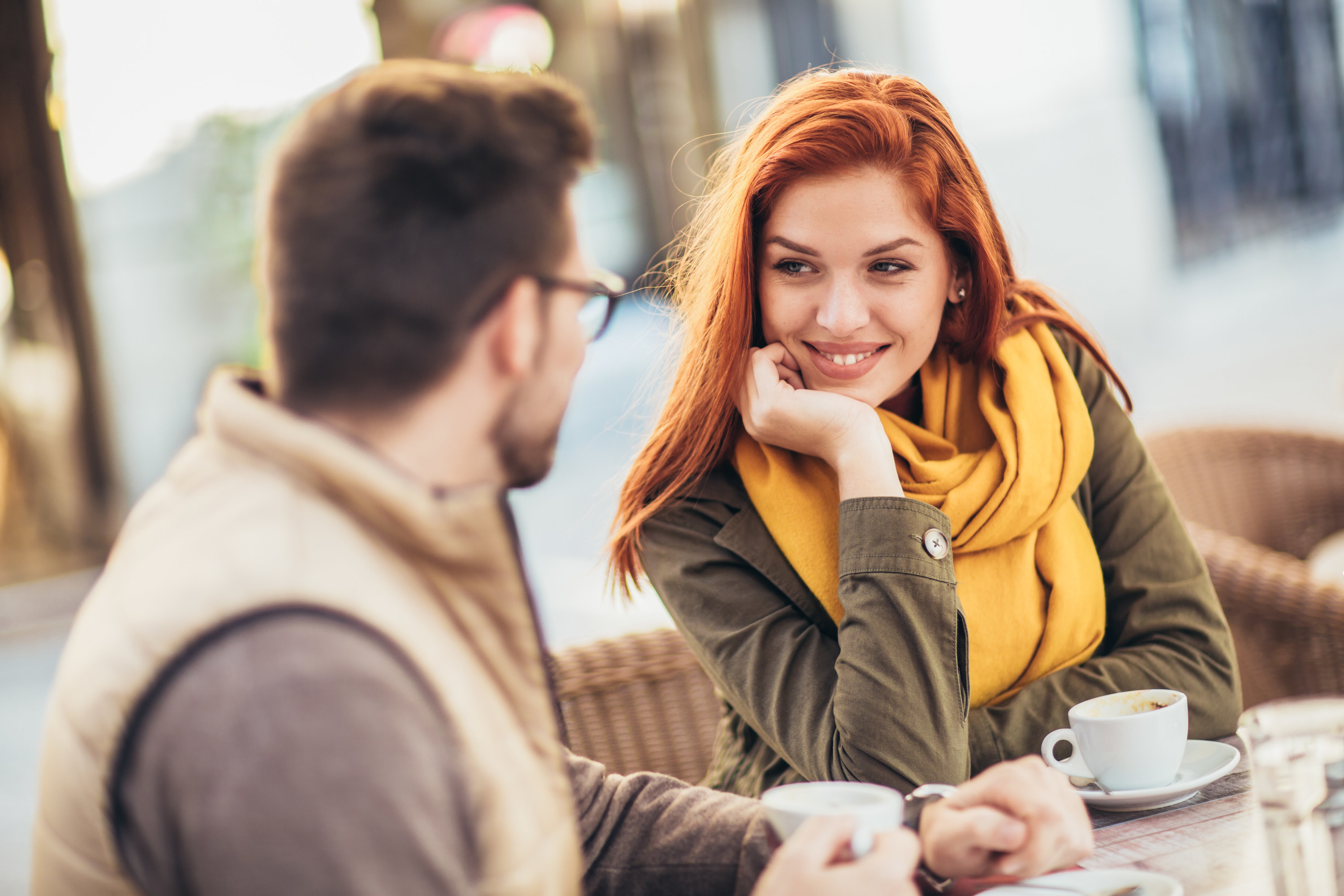 A woman smiles at a man during a coffee date