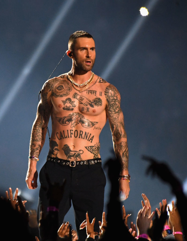 A tattooed, shirtless Adam Levine performing