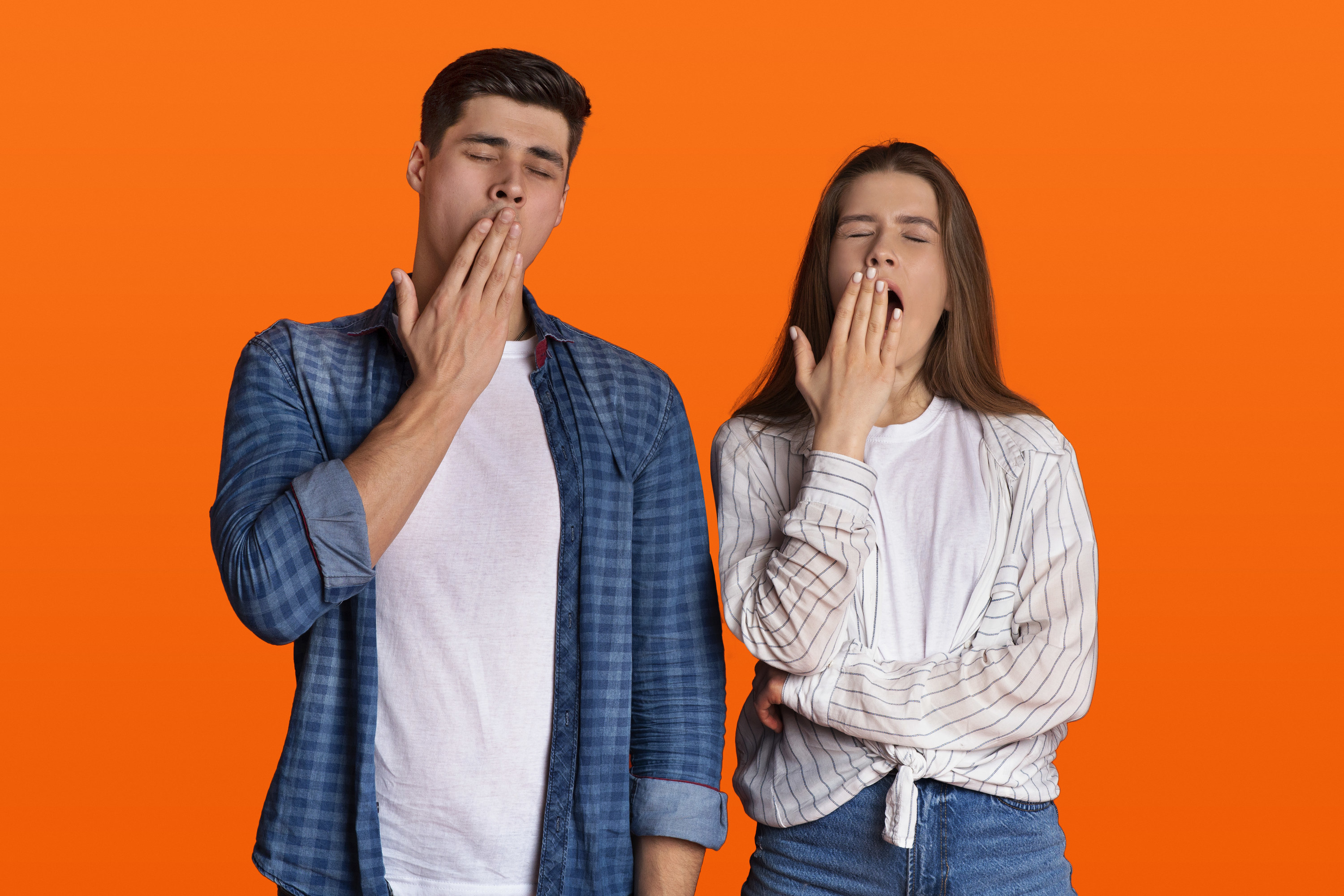 A man and a woman yawn next to one another