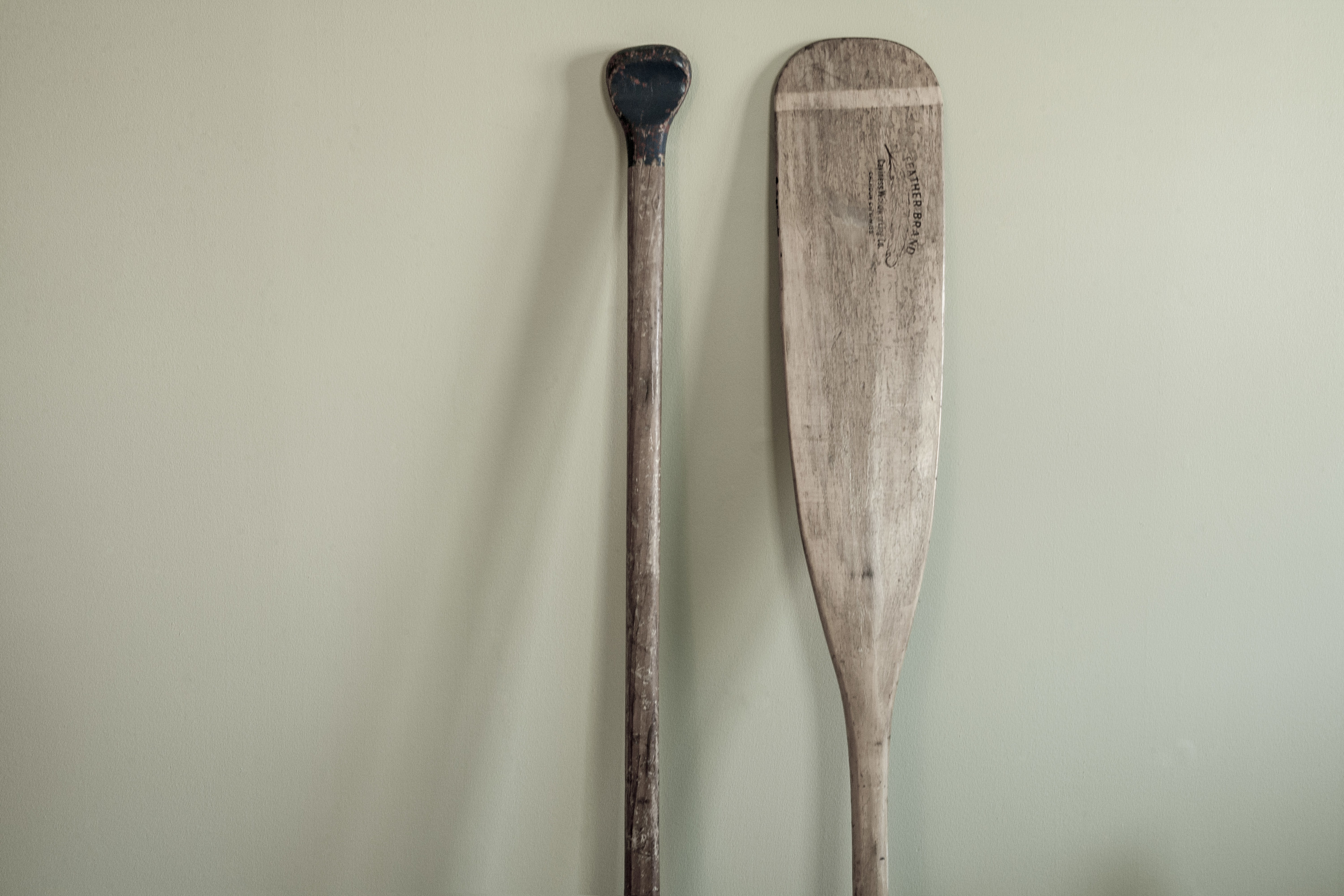 two wooden boat oars against a wall