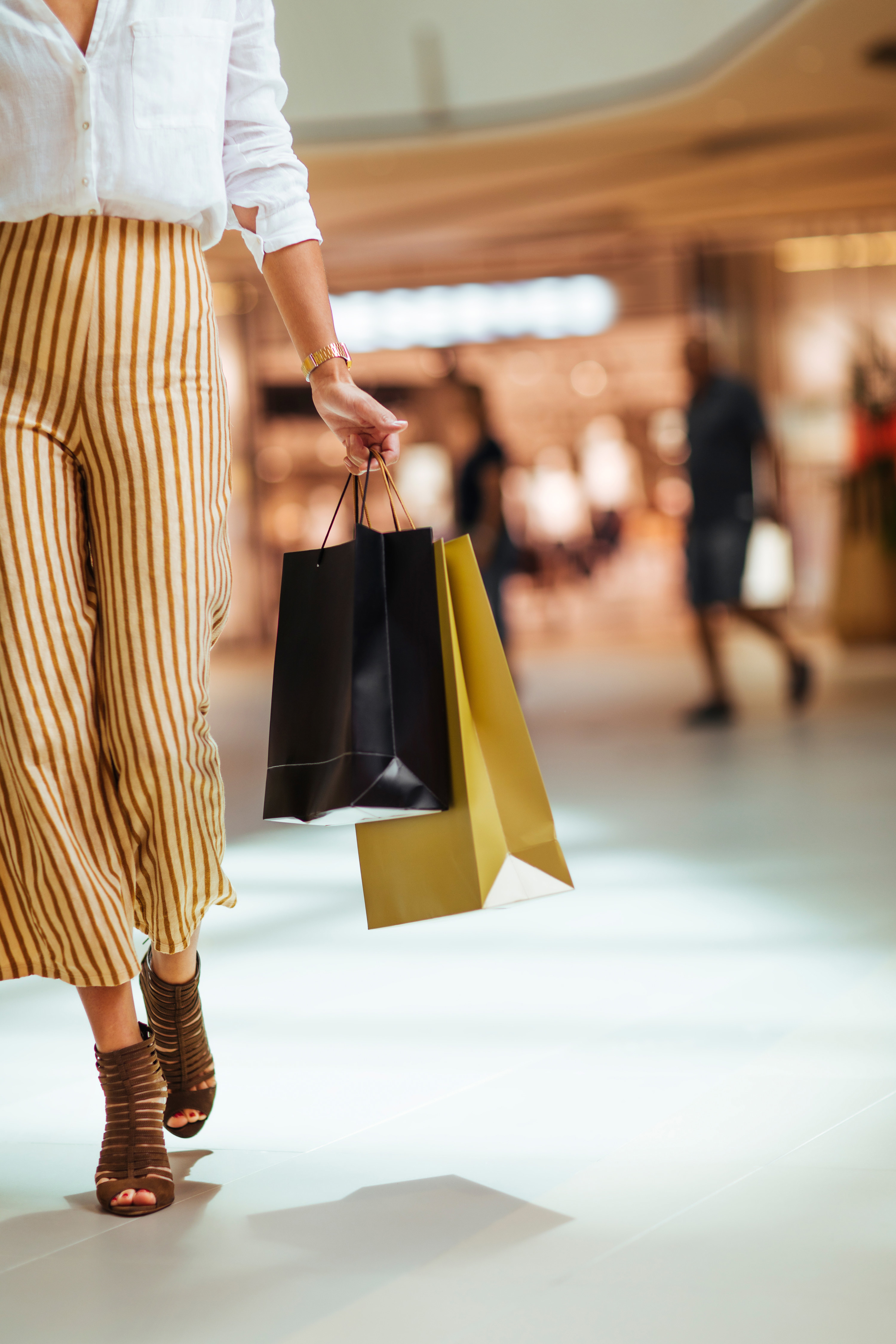 A woman carries a couple of shopping bags while walking through the mall