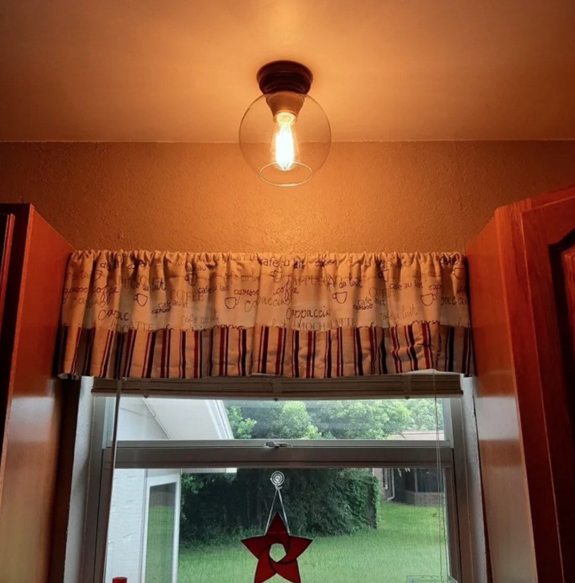 Glass globe flush mount light on ceiling in front of window