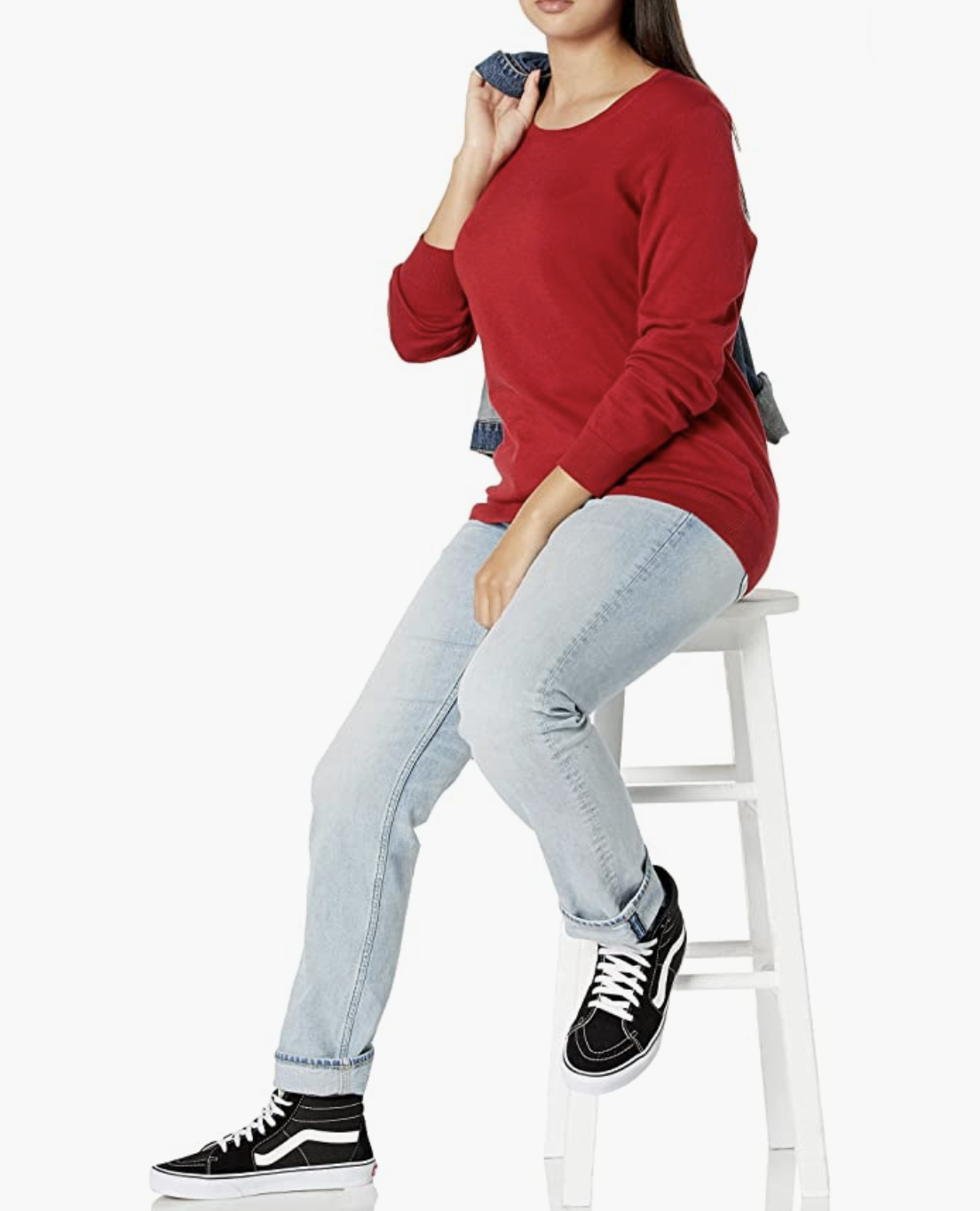 a person wearing the sweater with jeans while sitting on a stool