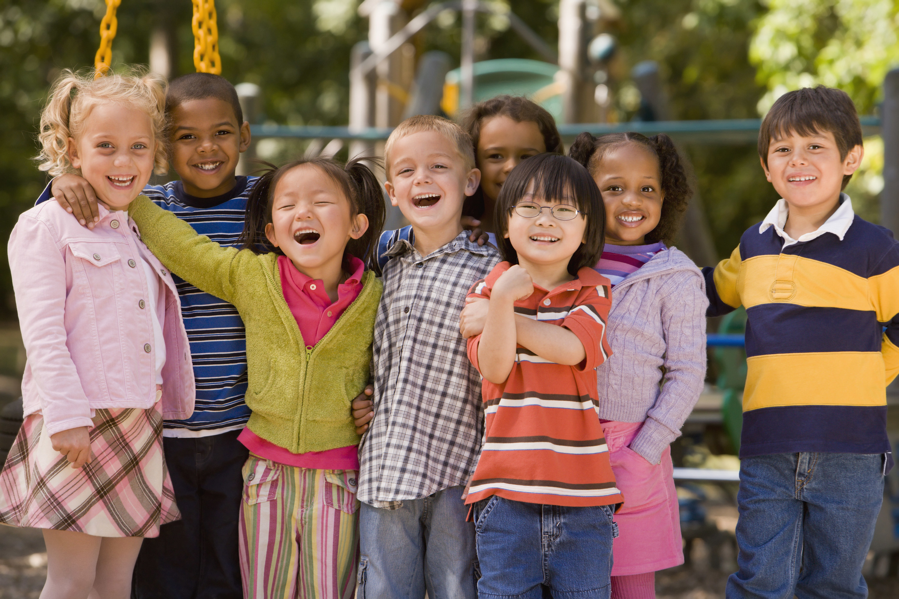 A group of five-year-old children smile on a playground