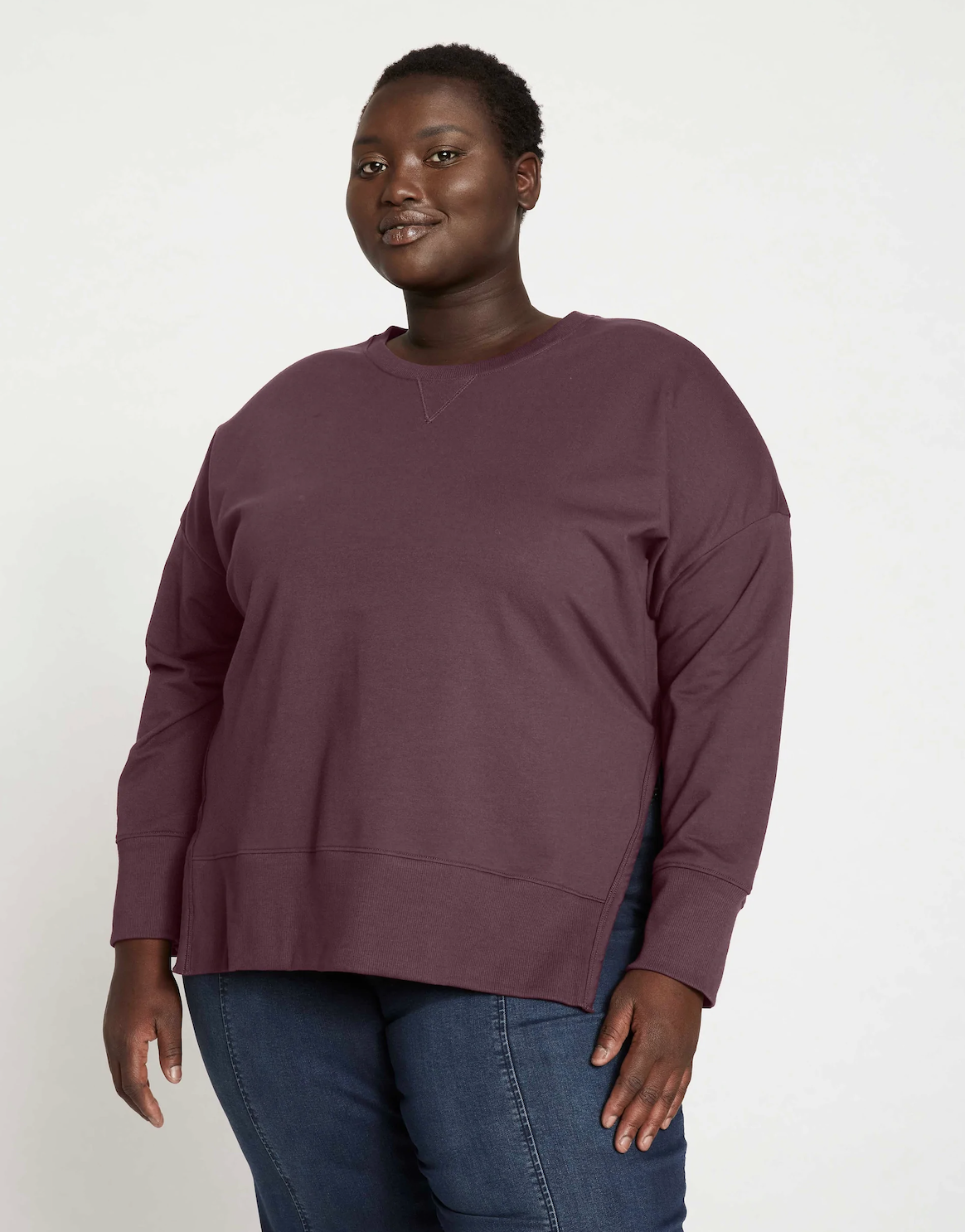 a model wearing the sweater with a pair of jeans in front of a plain bacgkround