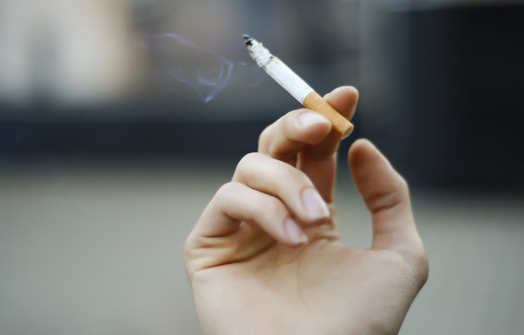 a hand holding a lit cigarette