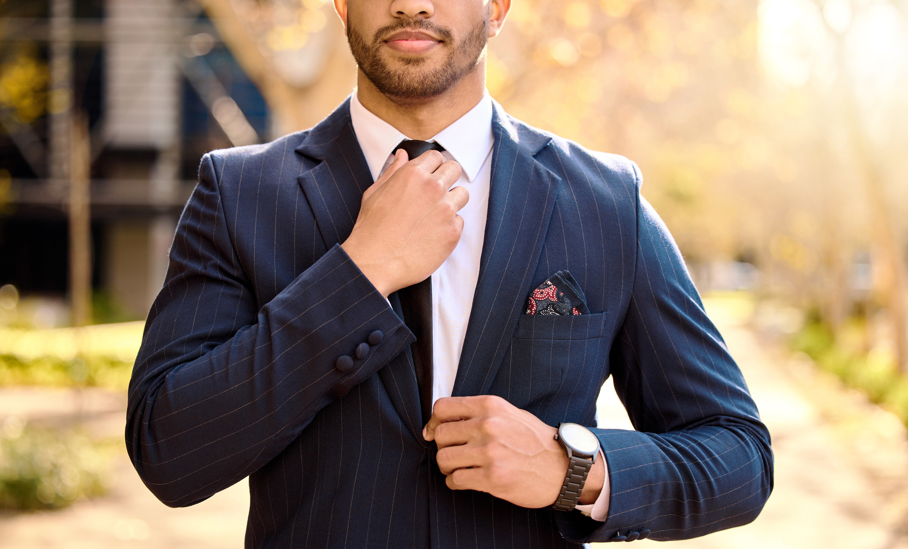 A man dressed in a suit fixes his tie