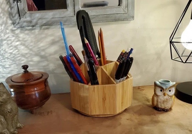 a bamboo rotating holder holding scissors, pens, and other supplies
