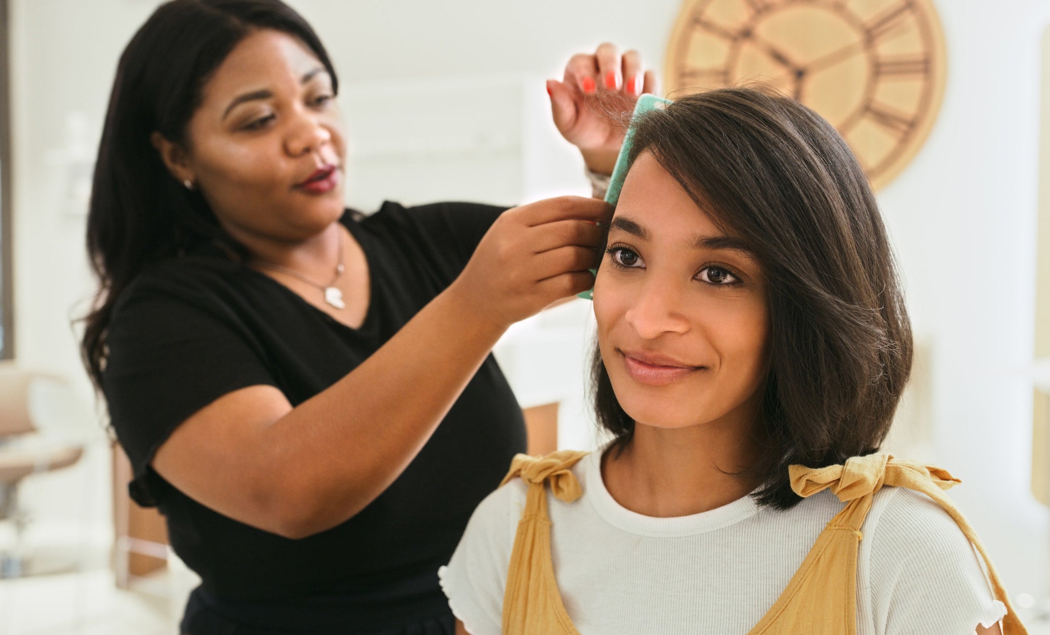 A woman doing another woman&#x27;s hair