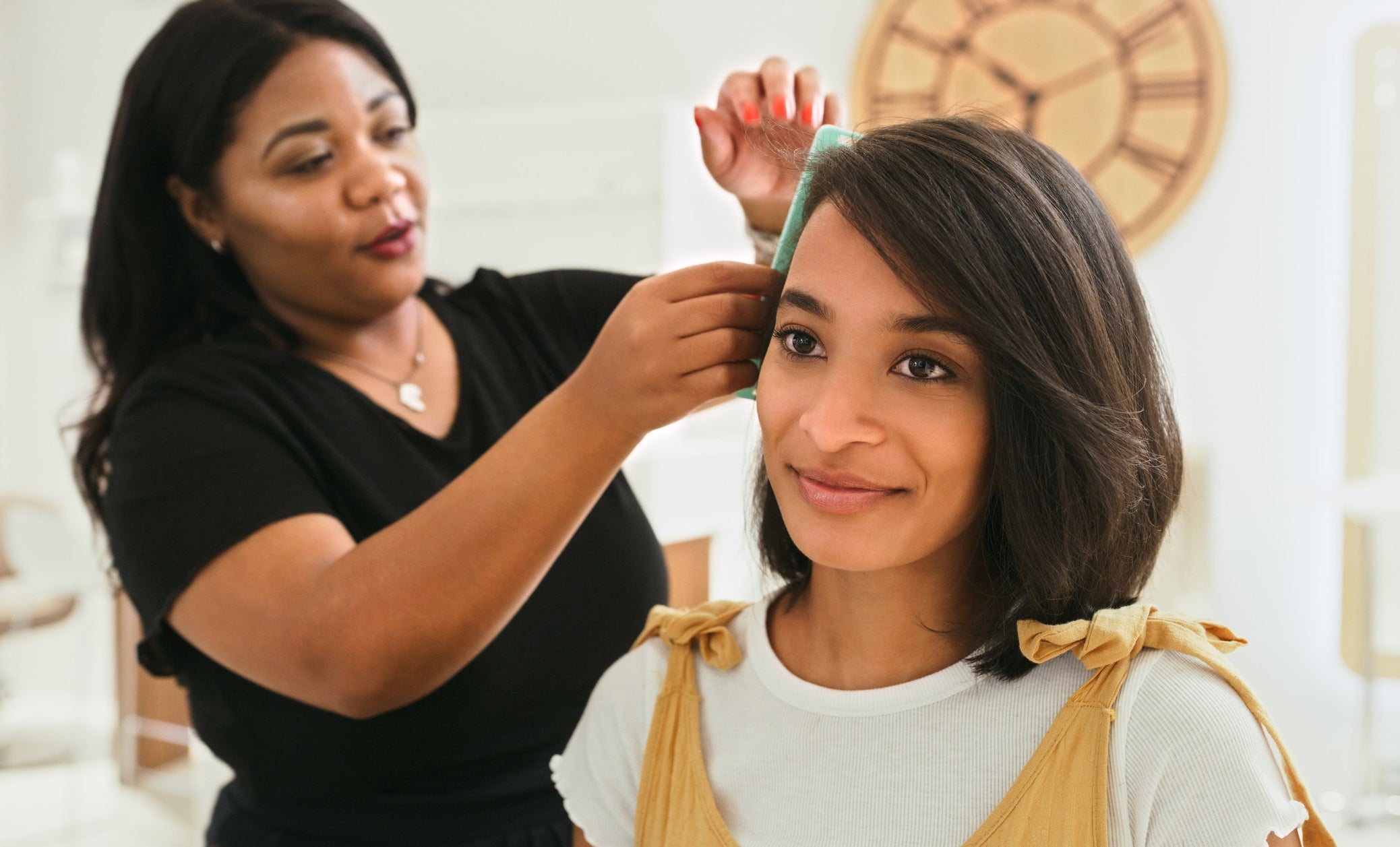 A woman doing another woman&#x27;s hair