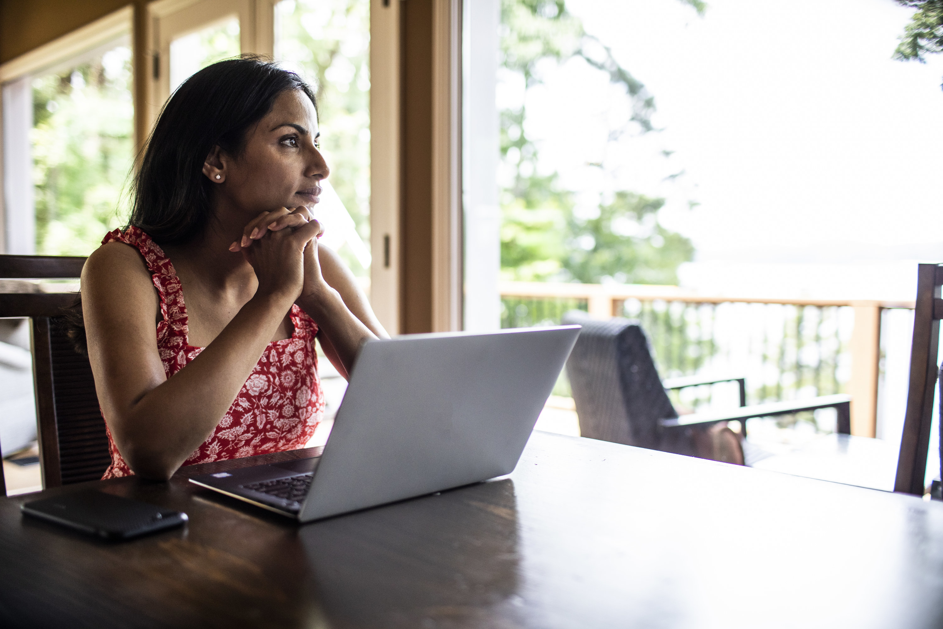 A woman is deep in thought as she sits behind her laptop