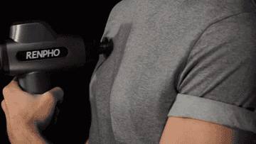 A person using the massage gun on their arm and chest