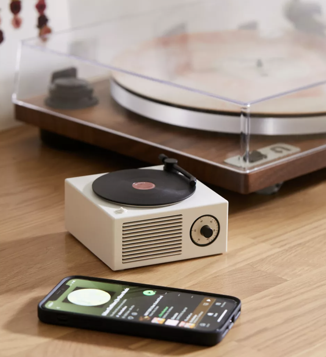 the tiny turntable next to a big turntable and a phone on a table
