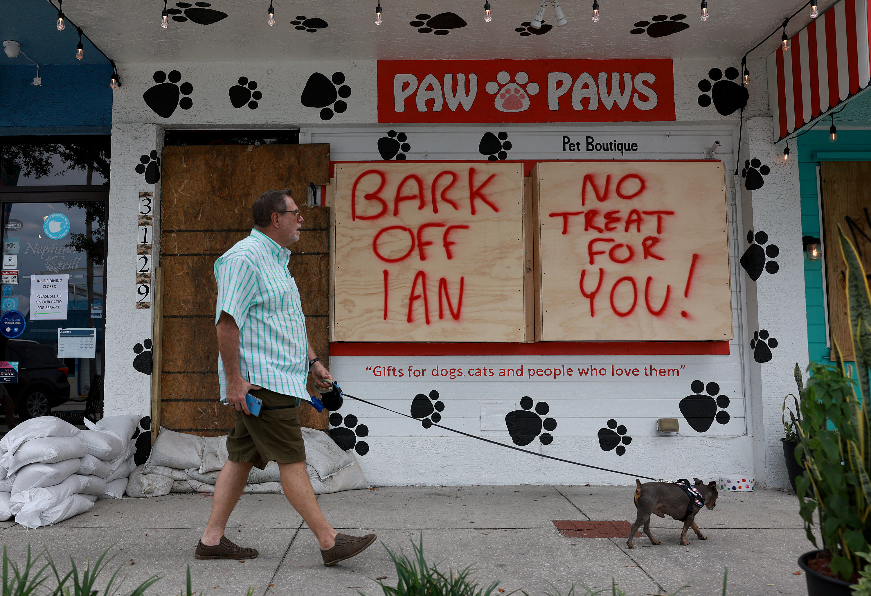 Boarded up windows on pet boutique have message &quot;Bark off Ian, No treat for you&quot; spray painted on them