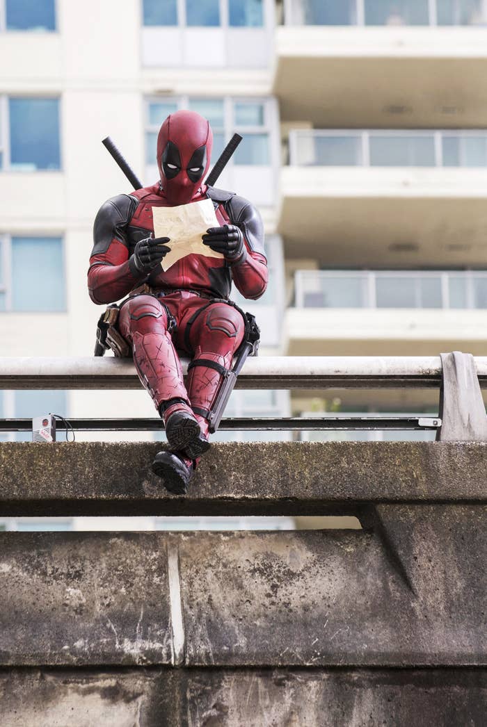 Deadpool sitting and reading a piece of paper