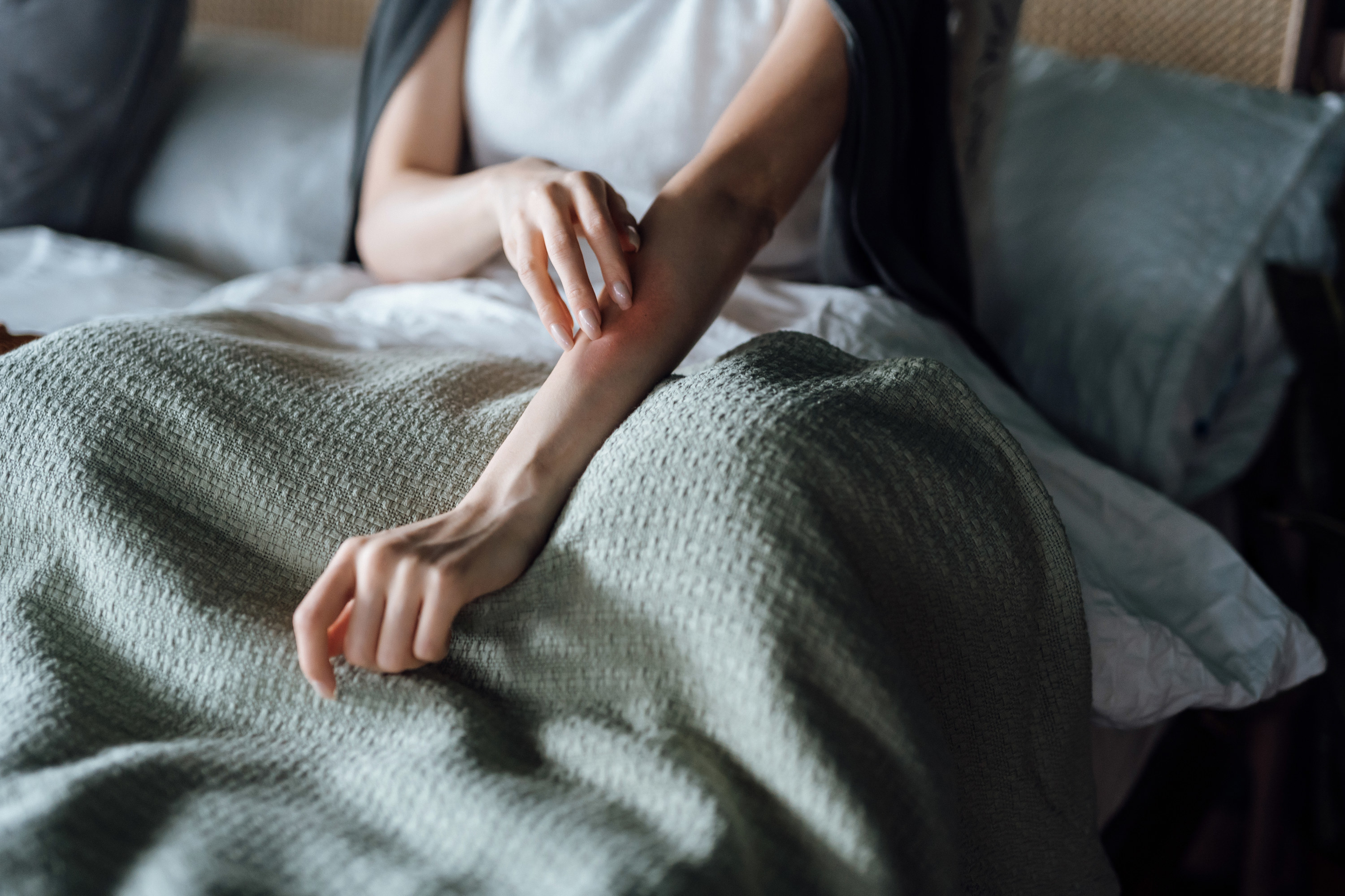 a woman touching her arm while in bed