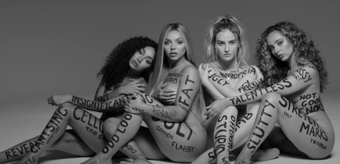 Little Mix in their music video with the mean comments written on their bodies