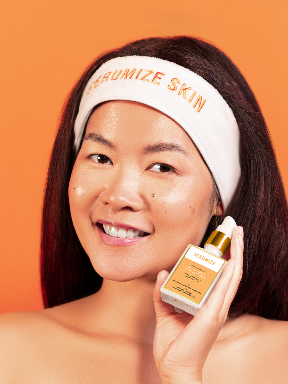 a smiling person holding up a bottle of the hydrating serum to their face