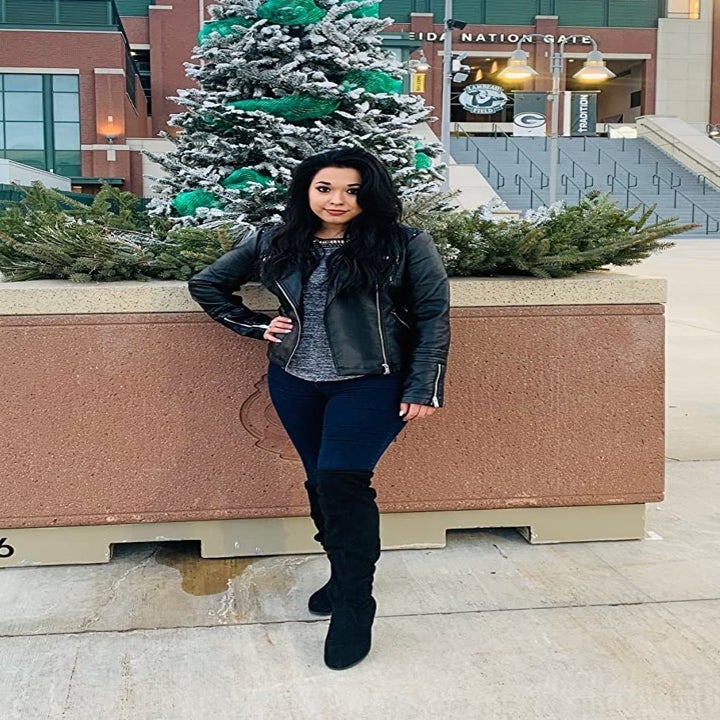 Reviewer standing in front of stadium in the black moto jacket layered open over top