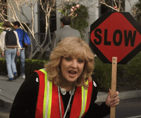 A crossing guard standing in front of a &quot;Slow&quot; sign