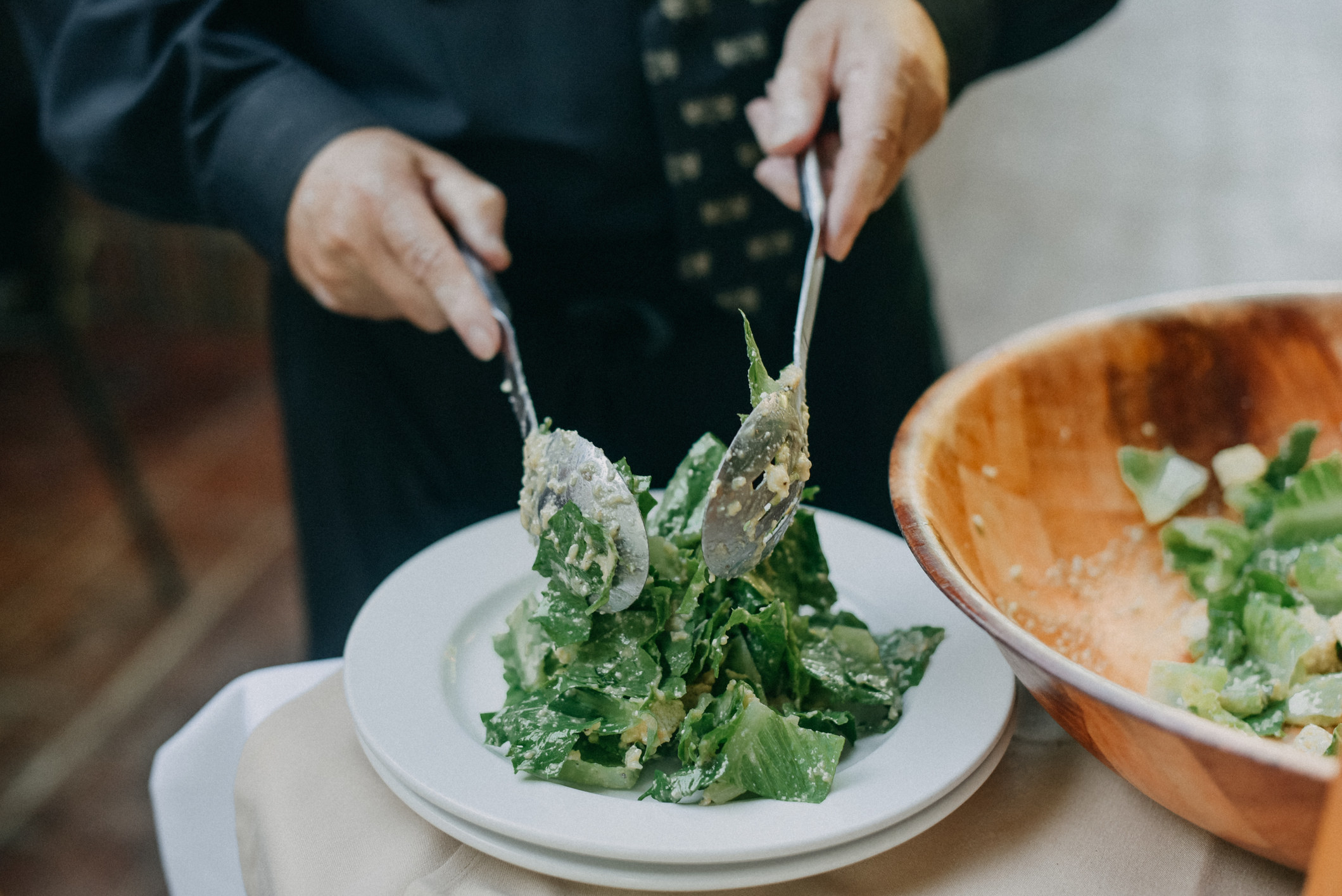 A waiter scooping salad onto a plate