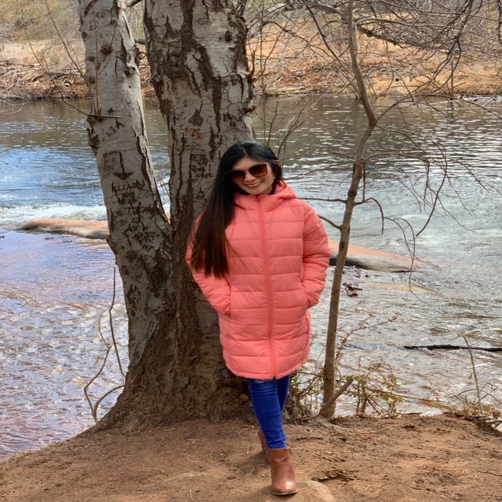Reviewer wearing the pink puffy coat and standing next to river