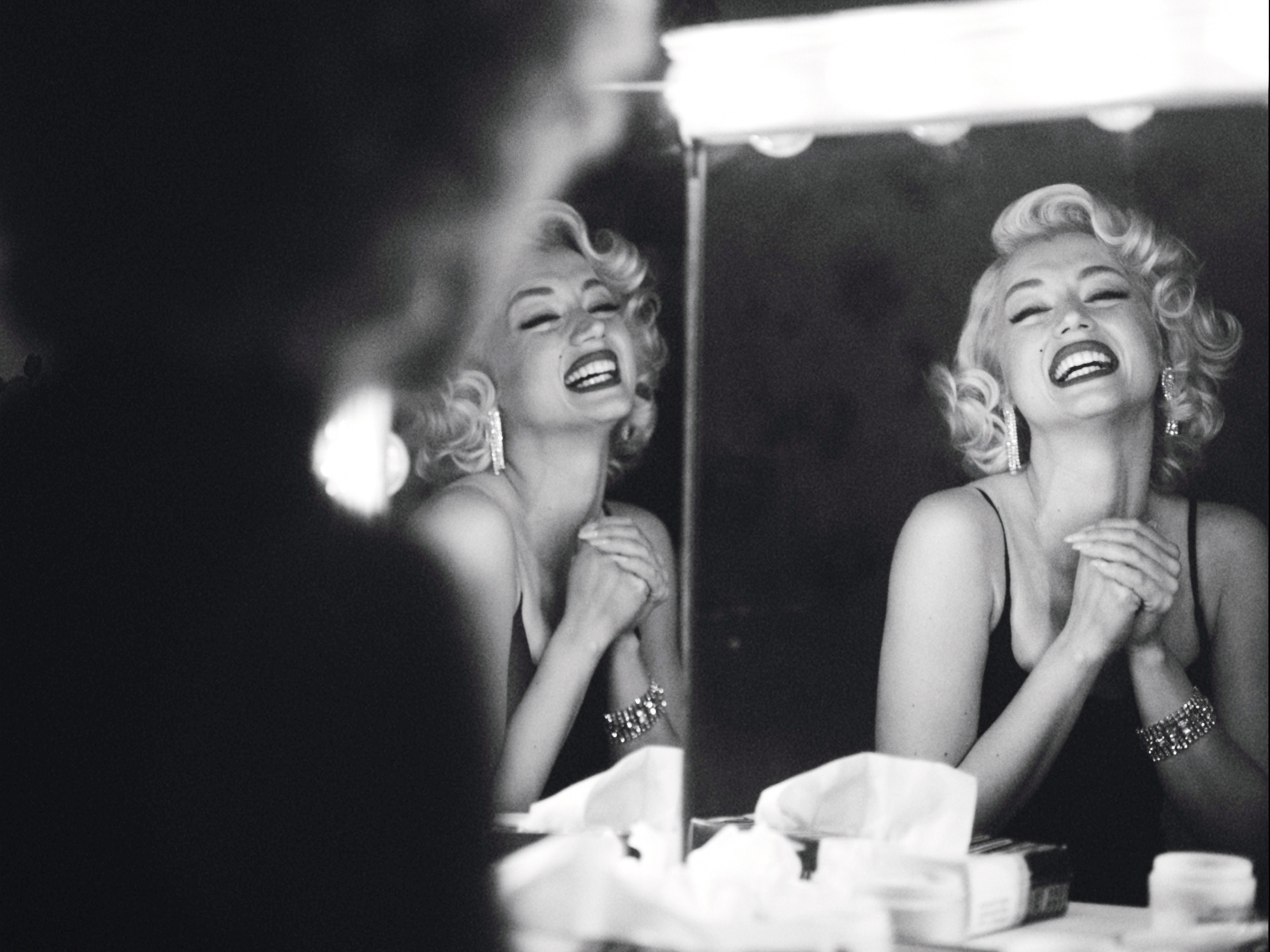 Ana de Armas as Marilyn Monroe smiling widely while in front of a mirror