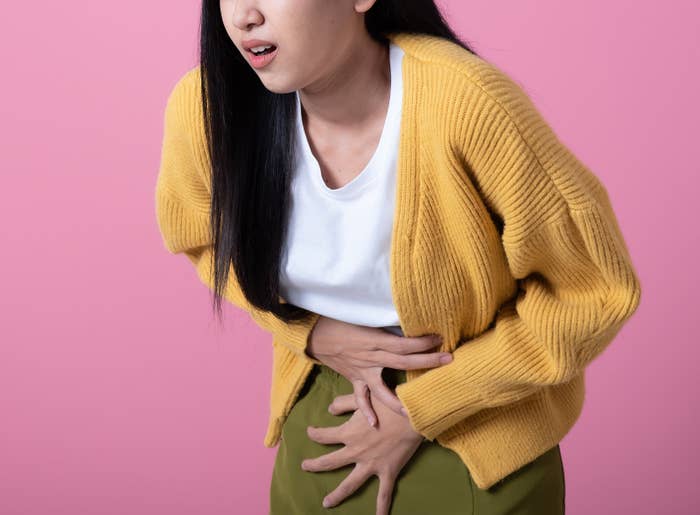 A woman experiencing stomach pains places her hands on her belly