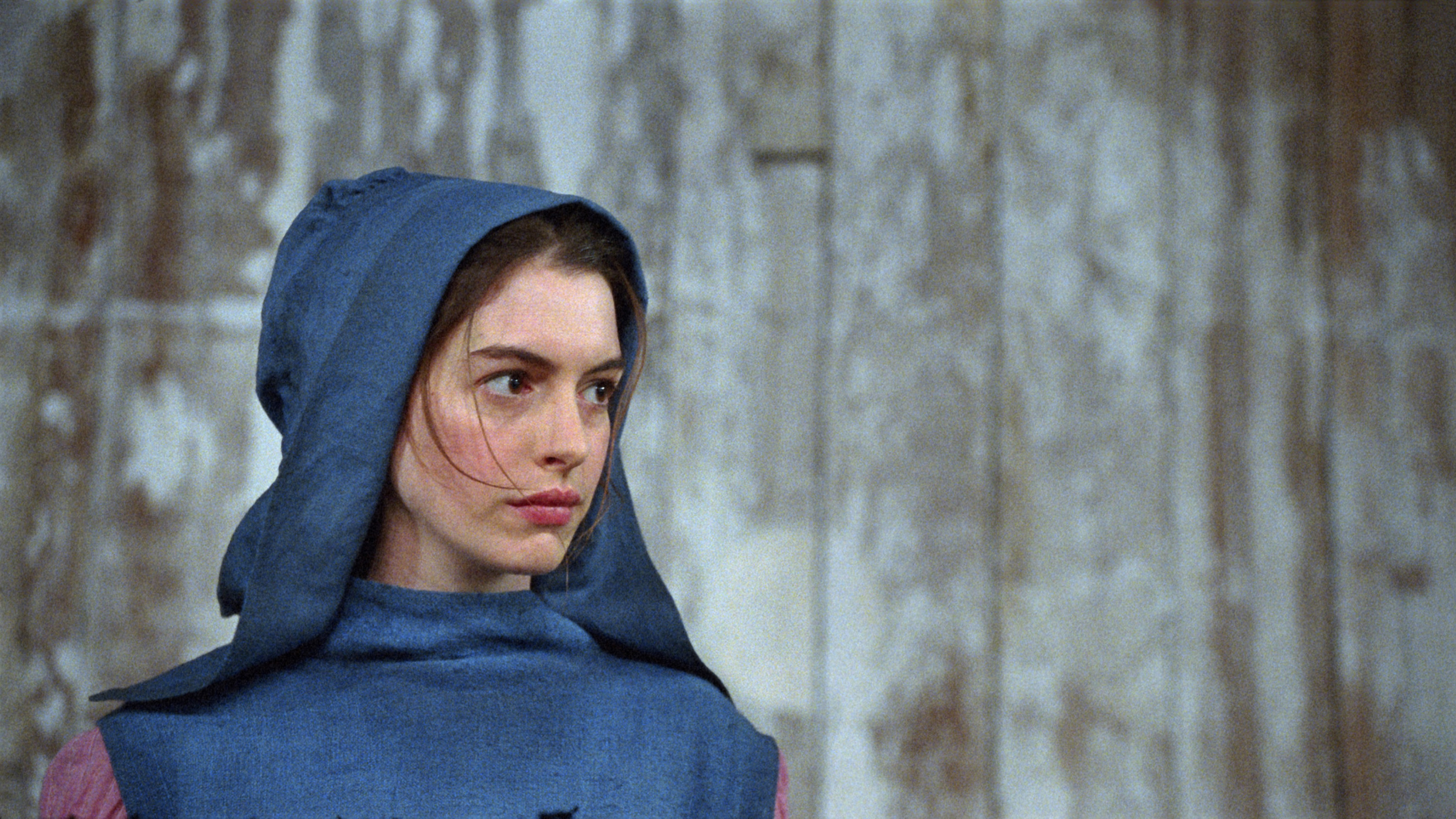 closeup of Hathaway&#x27;s character wearing a hood pulled over her head
