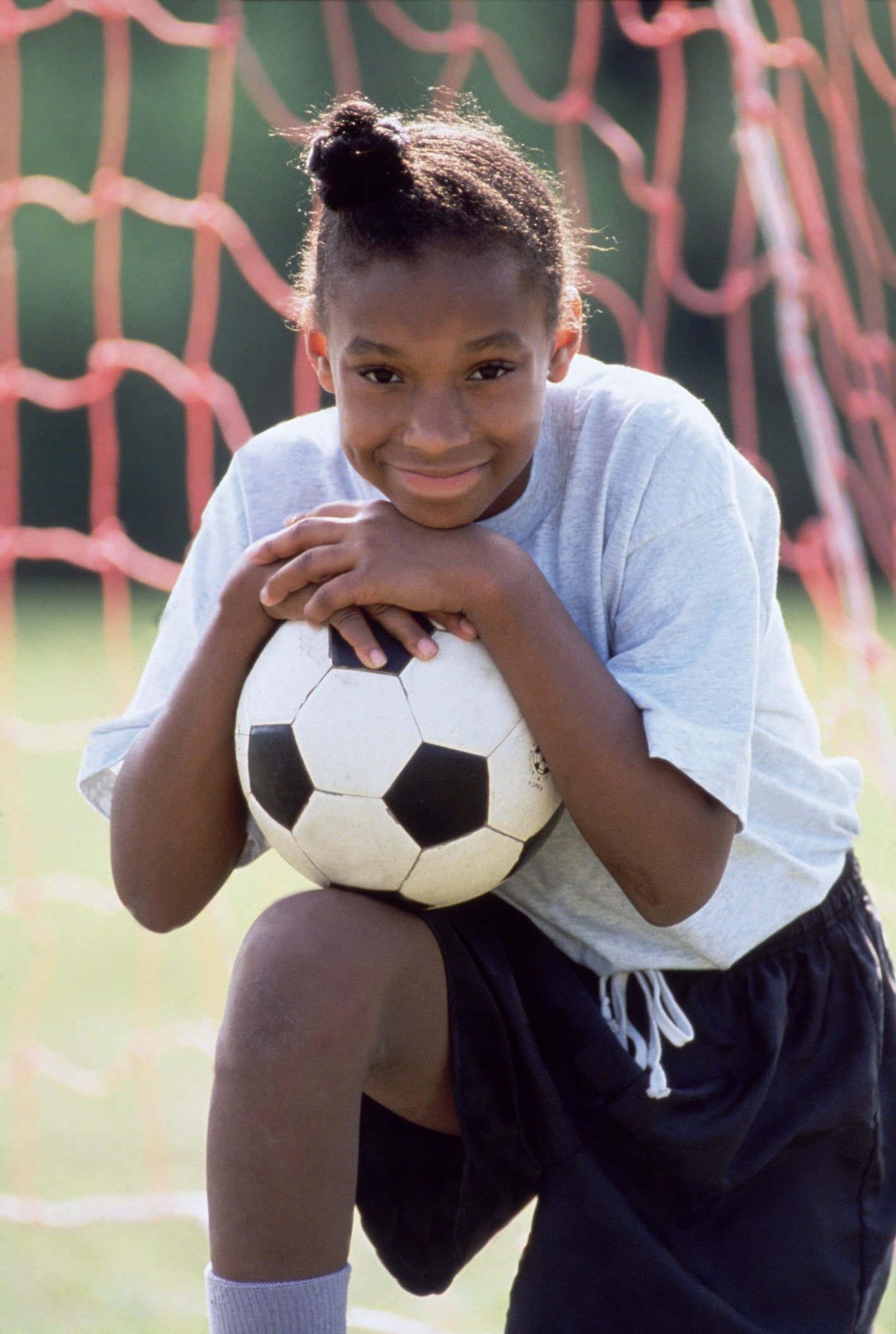 Girl kneeling with a soccer ball
