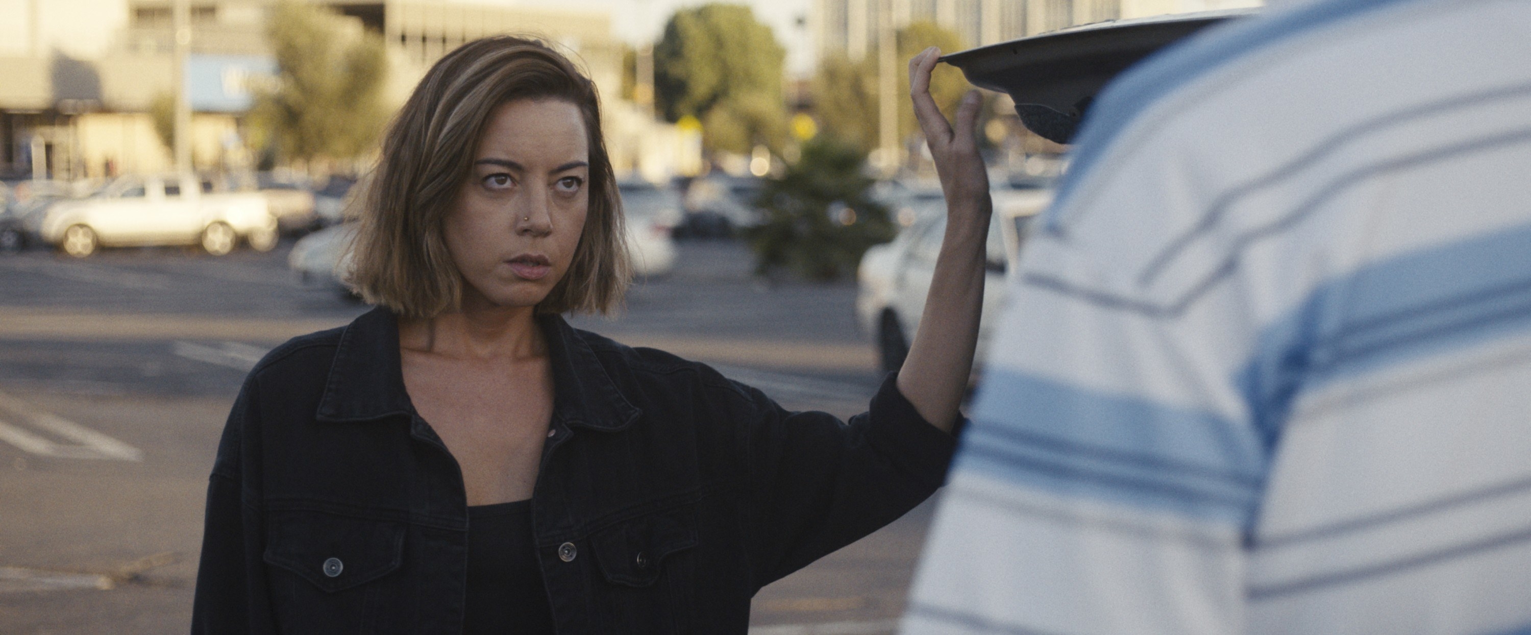 Aubrey Plaza stands in a parking lot