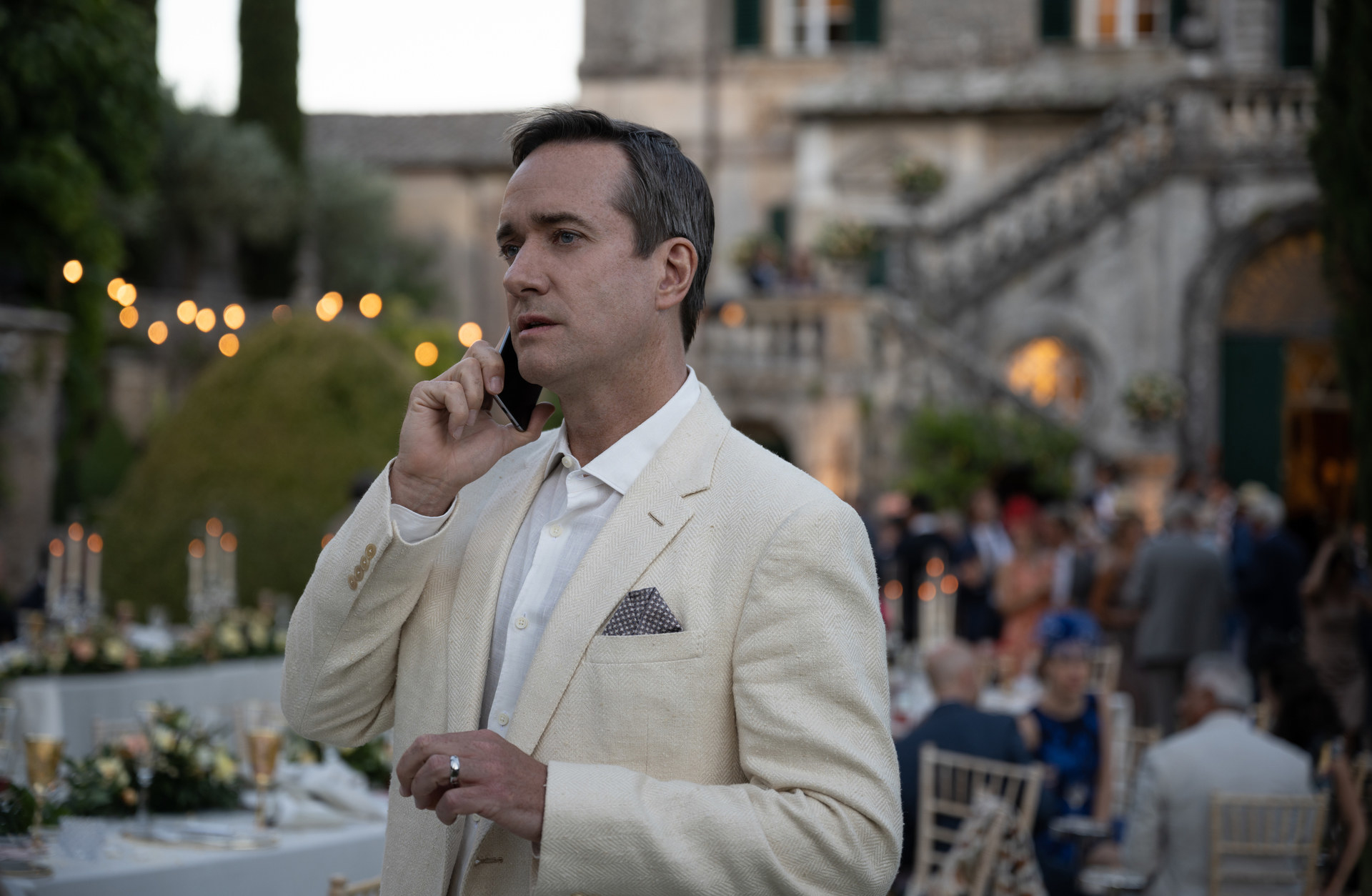 Matthew Macfadyen stands on his phone at a wedding