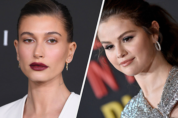 Hailey Bieber wears a white blazer top with bold red lipstick. Selena Gomez wears a sparkly cross-shoulder top with silver hoop earrings.