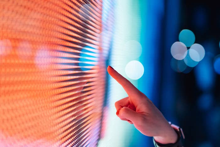 A finger touching a bright interactive wall screen