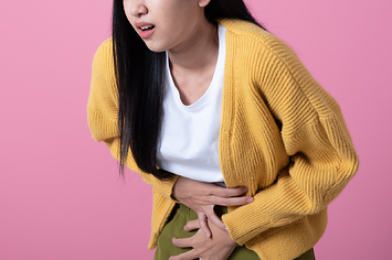 A woman experiencing stomach pains places her hands on her belly