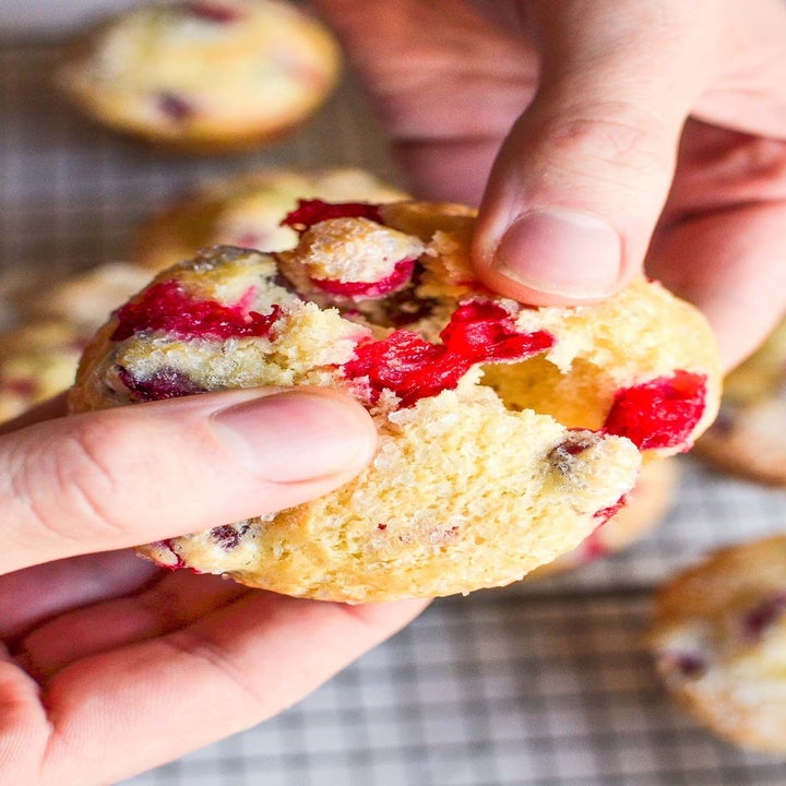 Hands breaking open a cranberry muffin.