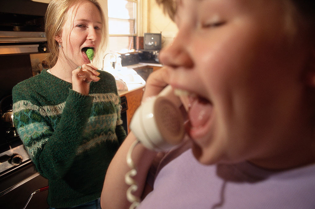 a person on a landline as a teenager stands by