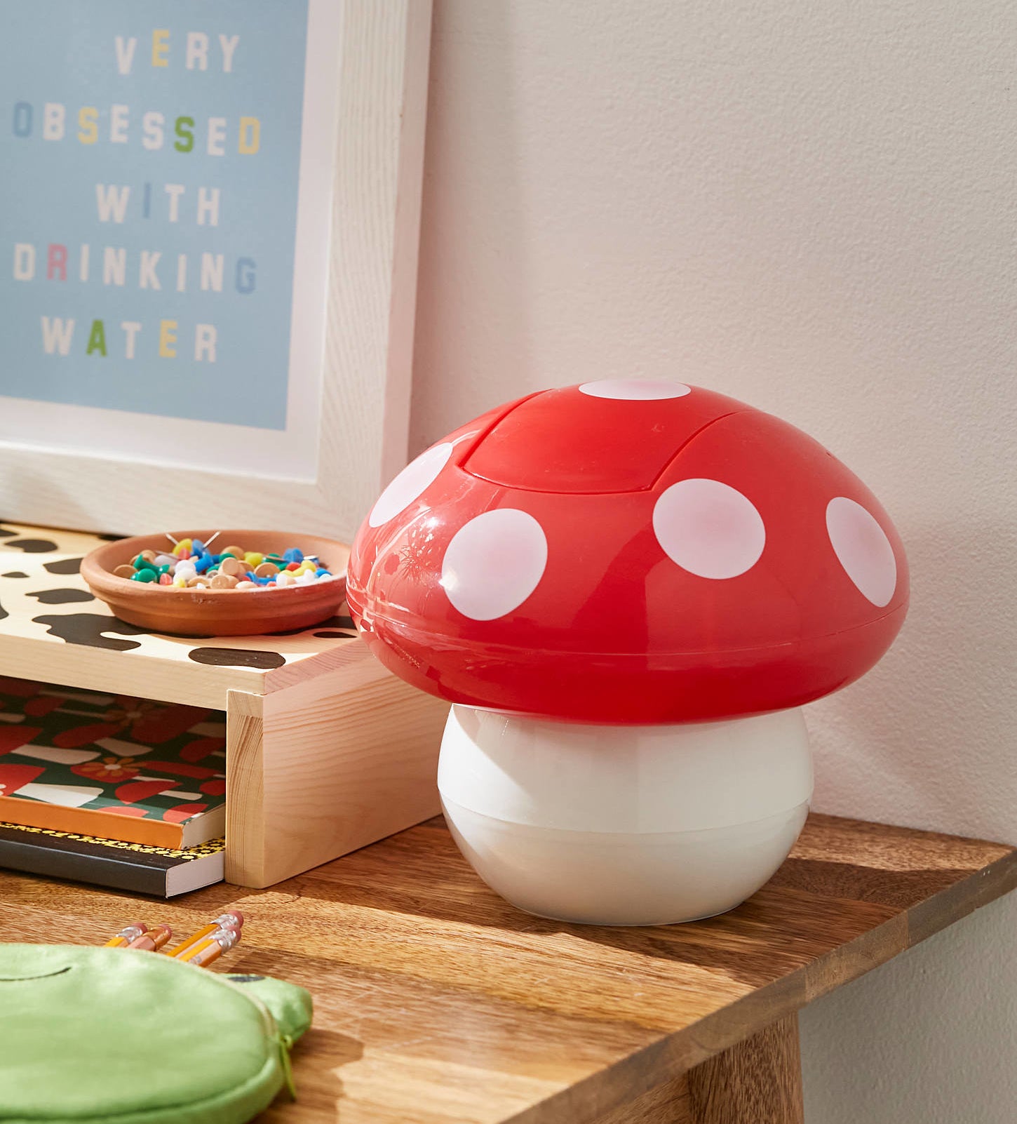 a mushroom-shaped trash can on a wood desk