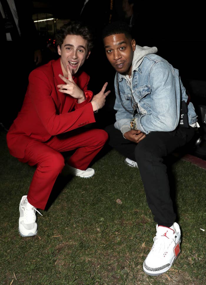 Timothée and Cudi crouching to pose for a photo