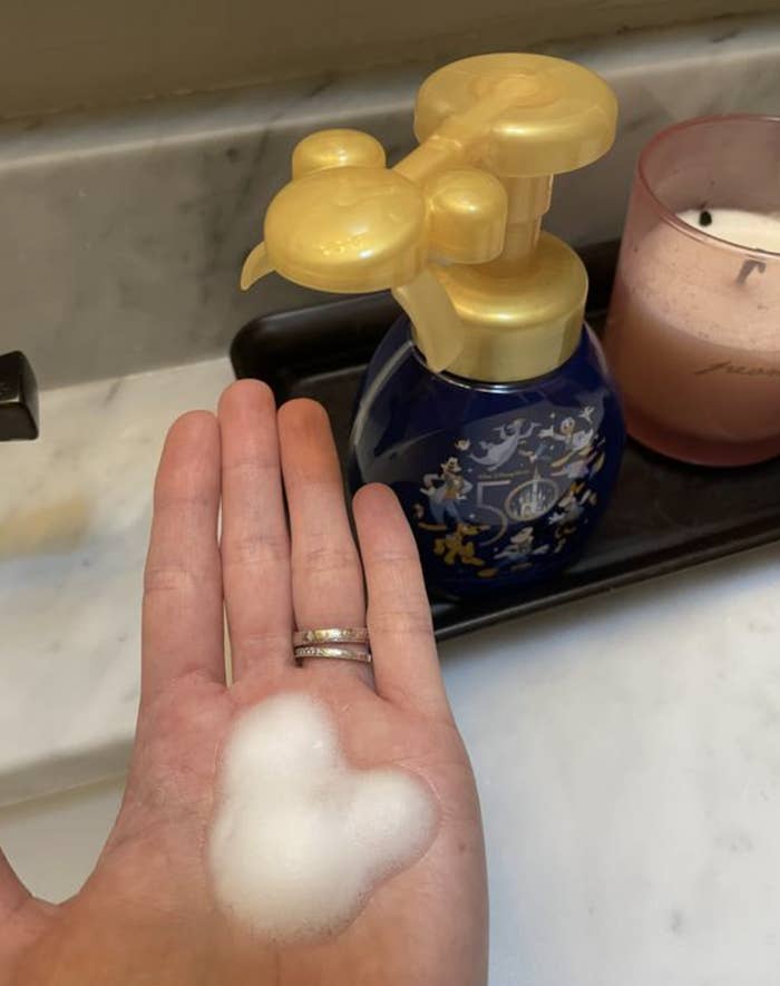 A reviewer's hand with a soap foam image of mickey mouse