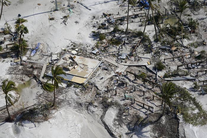 Aerial view of the ground shows a destroyed home, branches, and debris