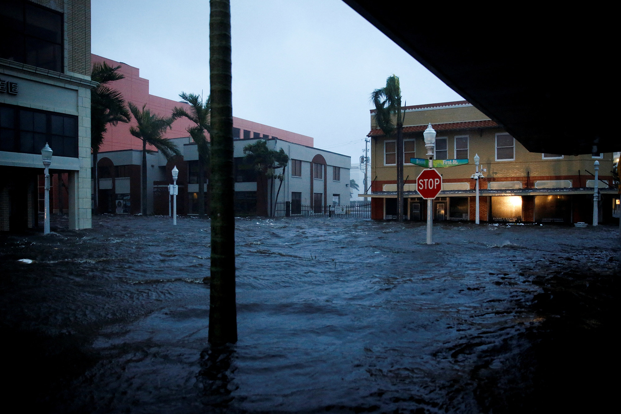 Water submerges a street, reaching at least half the height of buildings&#x27; first floors