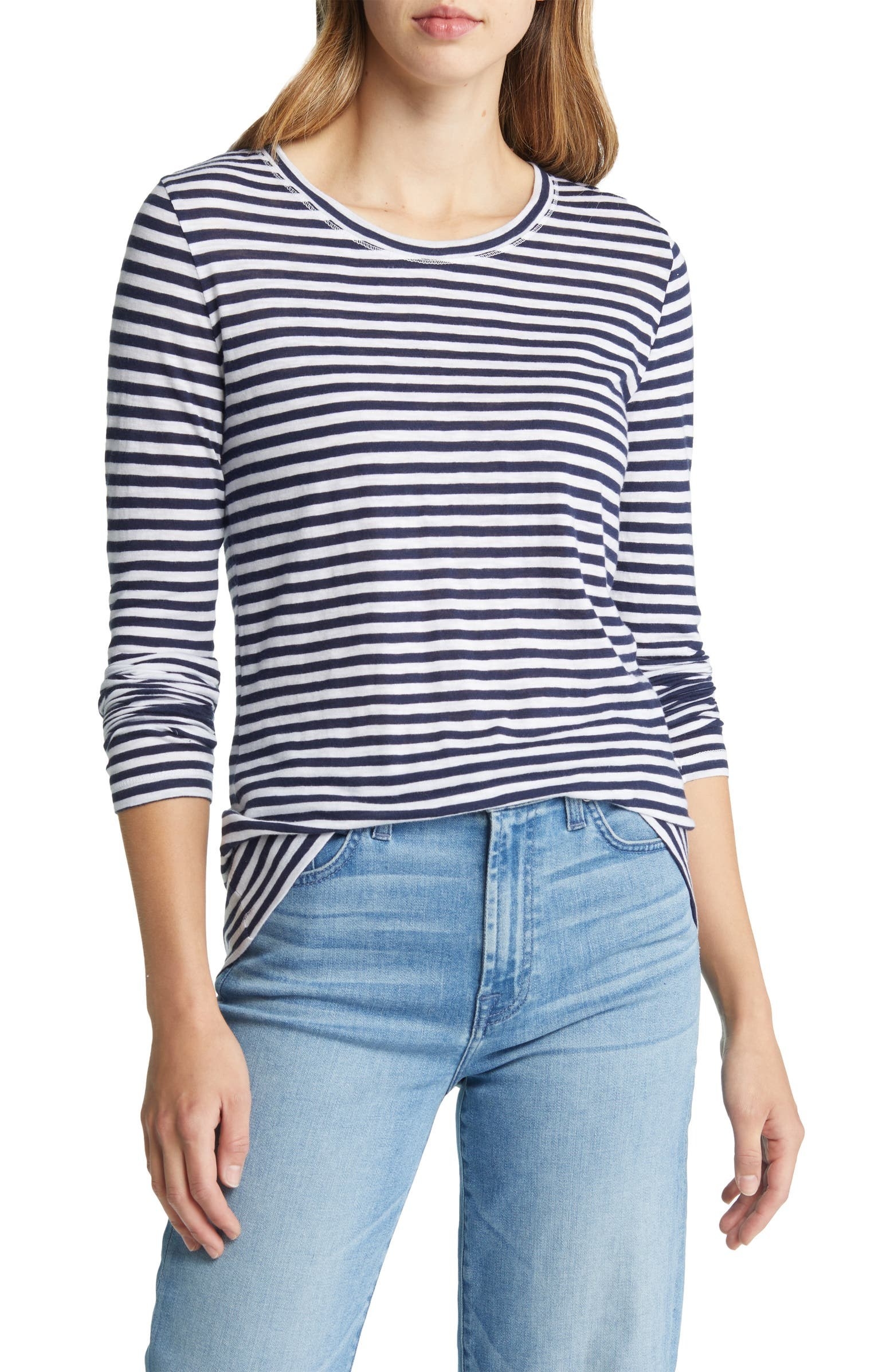 Modeling wearing blue and white stripped shirt with the front tucked in to jeans