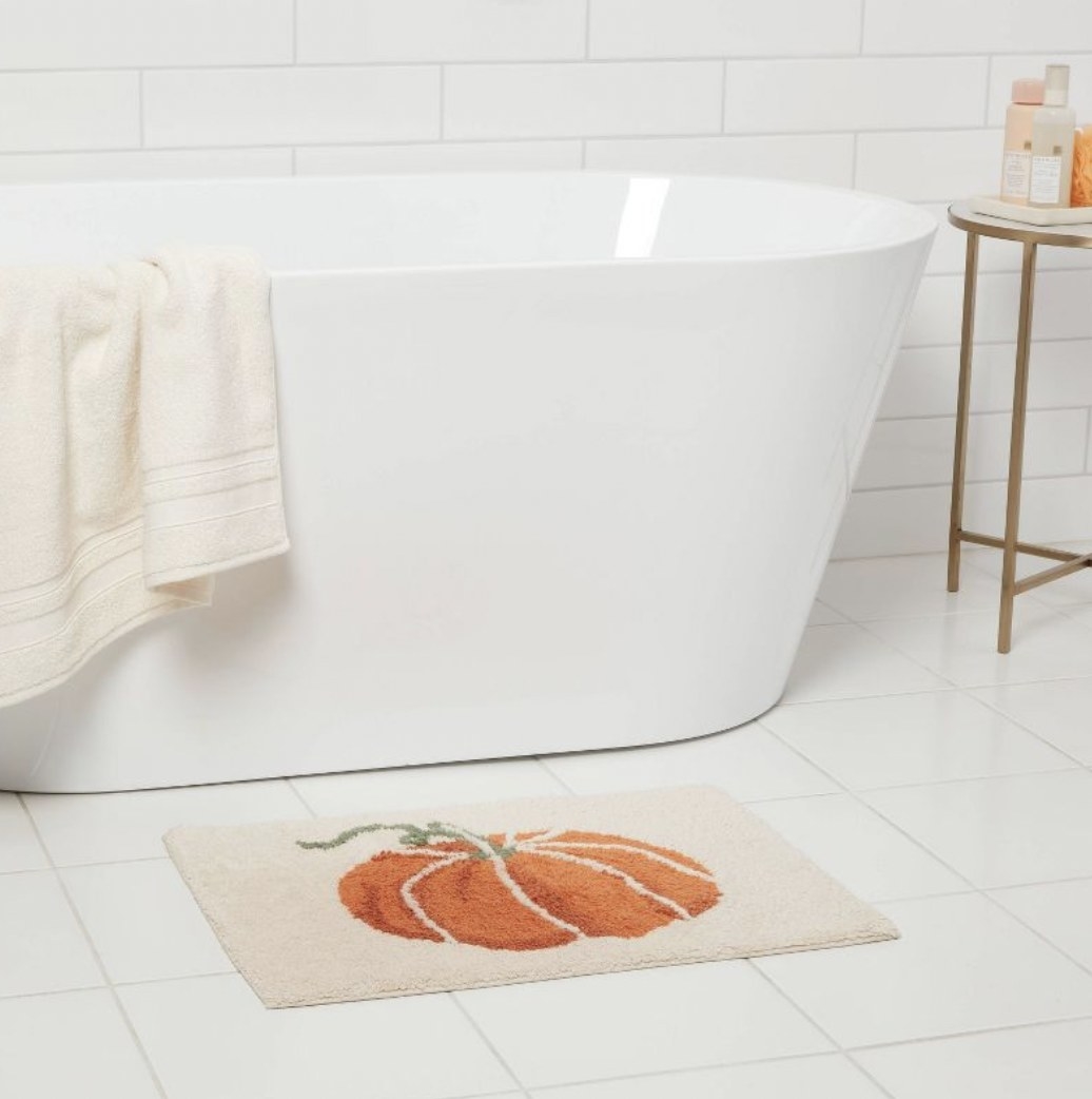 The cream bathmat with orange pumpkin design outside tub
