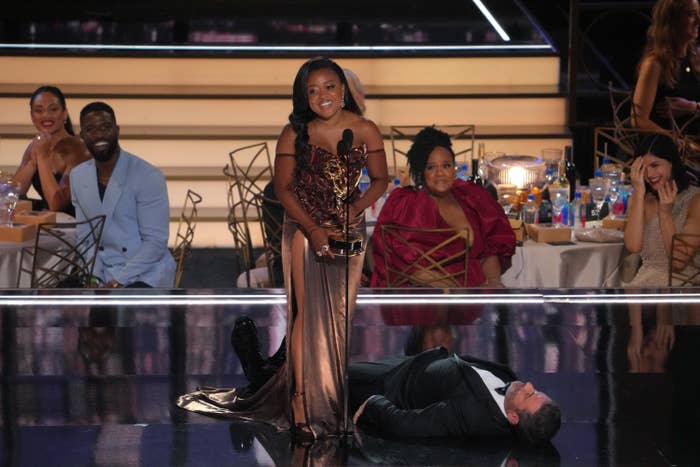 Quinta holds her Emmy while standing near Jimmy on the floor