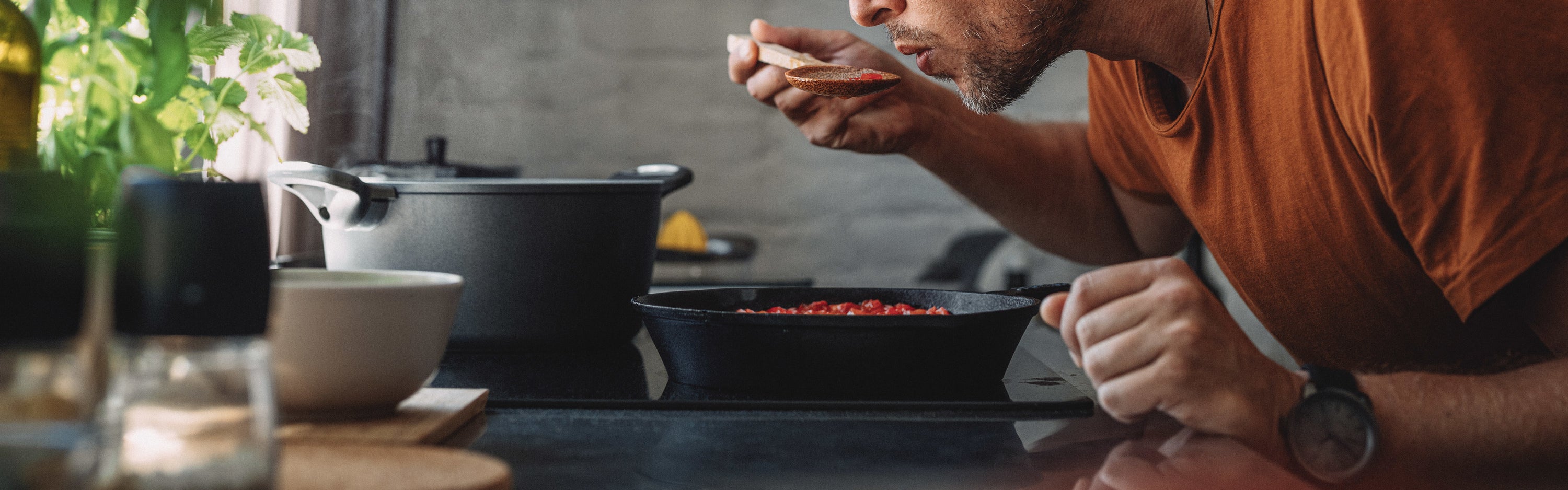 Close up shot of a man tasting sauce with a mixing spoon